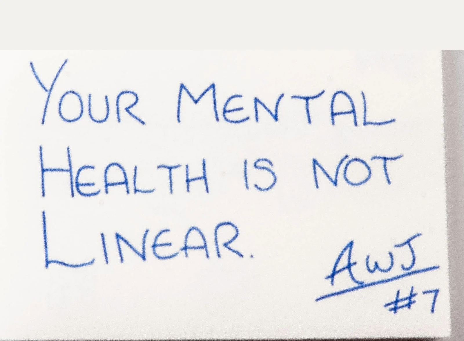 Handwritten in blue ink: Your mental health is not linear. Signed AWJ, number 7.