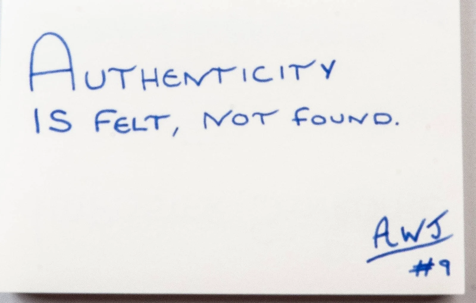 Handwritten in blue ink: Authenticity is felt, not found. Signed AWJ, number 9.