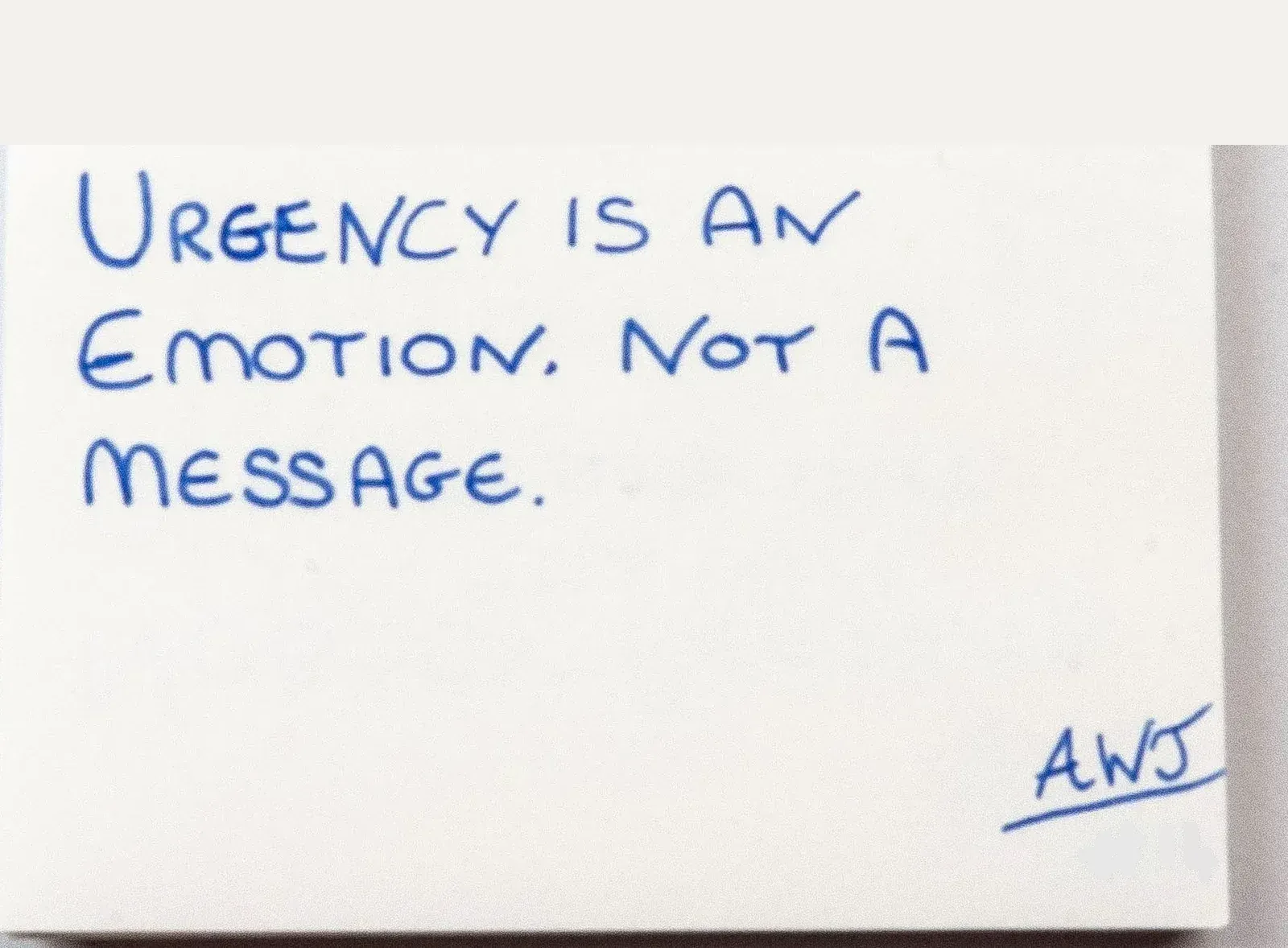 Handwritten in blue ink: Urgency is an emotion. Not a message. Signed AWJ, number 11.